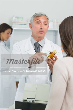 Apotheker mit dem Kunden auf einen Kolben von Pillen