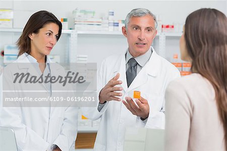 Pharmacien mâle, parler à un collègue en face d'un client de sexe féminin