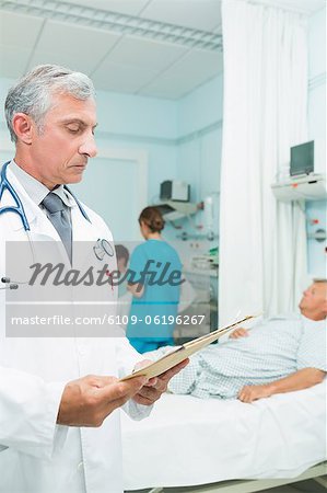 Doctor looking at a chart in a bed ward