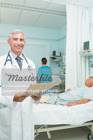 Happy doctor holding a chart in a bed ward