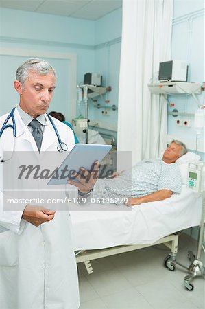 Serious doctor holding a tactile tablet while standing