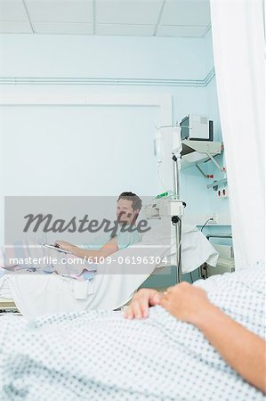 Souriant le patient dans une chambre d'hôpital avec un autre patient