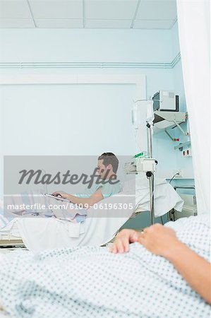 Focus shot of a patient holding a laptop while lying on a bed