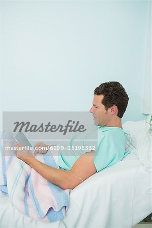 Patient touching a tactile tablet while lying on a bed