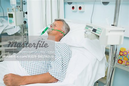 Unconscious patient lying on a bed with an oxygen mask on