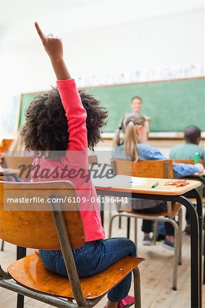 Back view of schoolgirl raising hand during class