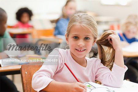 Lächelnd mädchen sitzen am Schreibtisch im Klassenzimmer