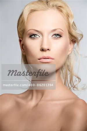 beautiful blonde girl with nudes shoulders and natural makeup, she is in front of the camera and looks in to the lens with sensal expression