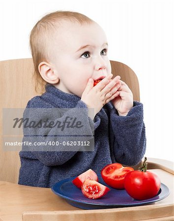 young child eating in high chair isolated in white backgound