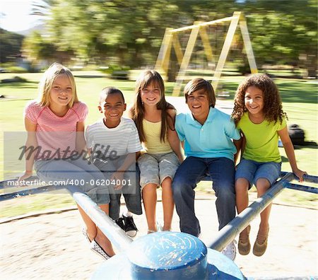 Group Of Children Riding On Roundabout In Playground