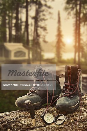 Hiking boots with compass on tree trunk at campsite