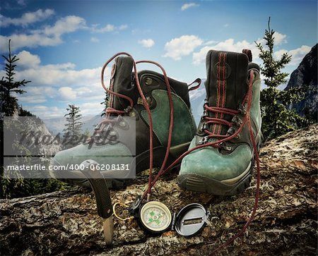 Pair of hiking boots with compass on fallen tree trunk