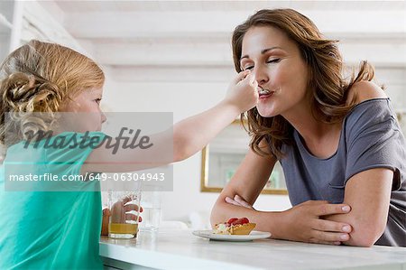 Girl feeding mother breakfast