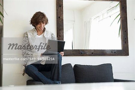 Teenage boy using laptop on sofa