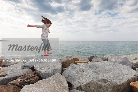 Girl playing on rocks at beach