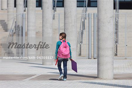 Girl carrying folder in courtyard