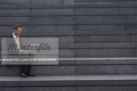 Businessman reading newspaper on steps