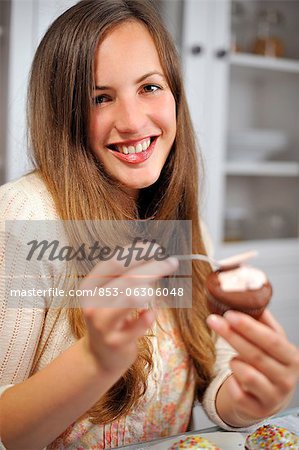 Young woman garnishing muffin, portrait