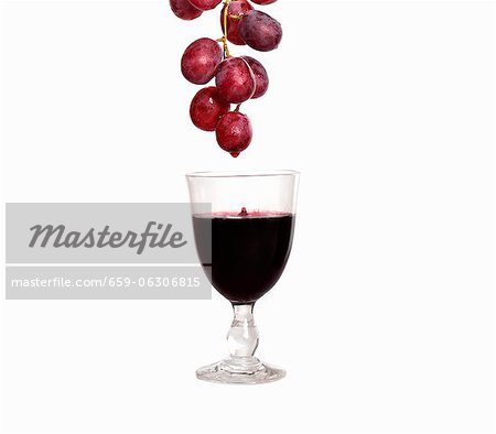 Tropft aus roten Trauben in Wein Glas Rotwein