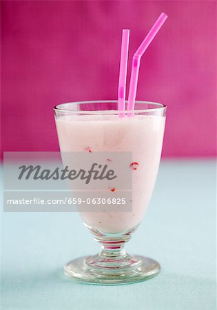 A strawberry smoothie in a glass with straws