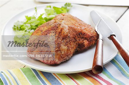 Seasoned Pork Roast on a White Platter; Fork and Knife