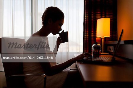 Young woman sitting at laptop in hotel room