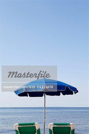 Bleus parasol et chaises longues au bord de la mer