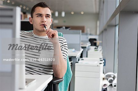 Man chewing pen at desk