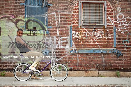 Portrait of a young woman on bicycle by wall covered in graffiti Portrait of a young woman on bicycle by wall covered in graffiti