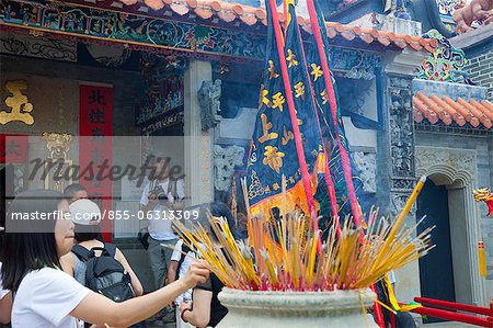 Worshipper offering incense at Pak Tai Temple during the Bun festival, Cheung Chau, Hong Kong
