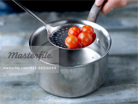Dipping the cherry tomatoes in the hot water to peel