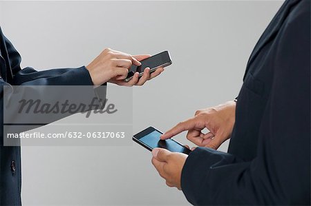 Colleagues exchanging information with smartphones, cropped