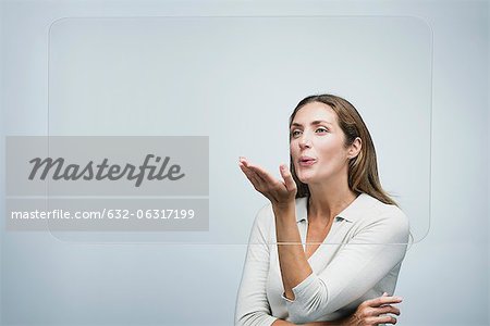 Woman blowing a kiss at large transparent screen