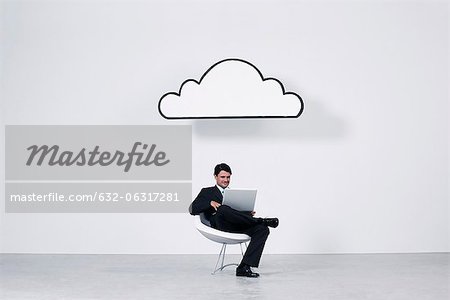 Homme d'affaires utilisant un ordinateur portable sous nuage représentant nuage informatique