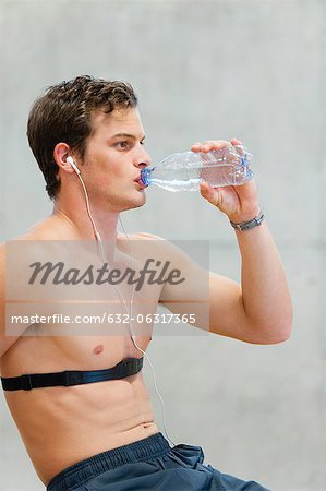 Barechested junger Mann trinken Mineralwasser
