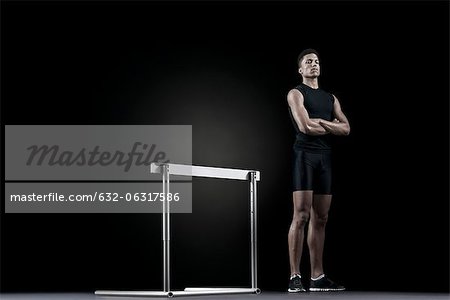 Male athlete standing by hurdle