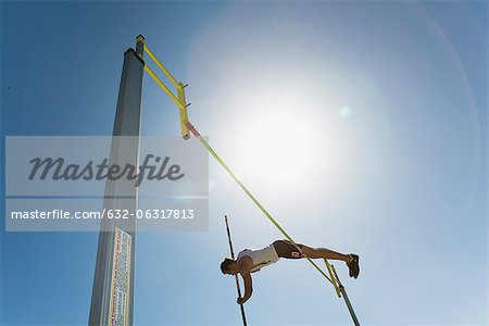 Male athlete jumping over high jump bar