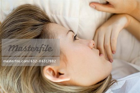 Woman lying down, looking away in thought