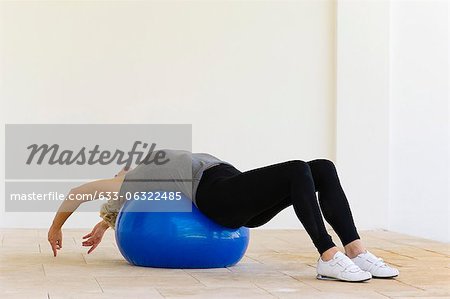 Woman lying on fitness ball stretching