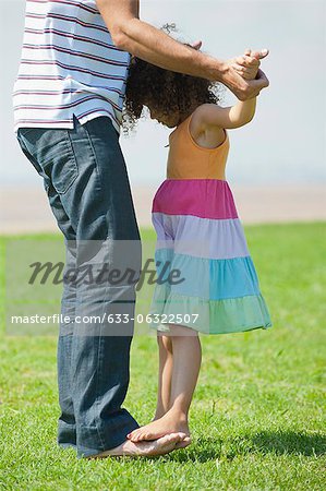 Girl standing on father's feet