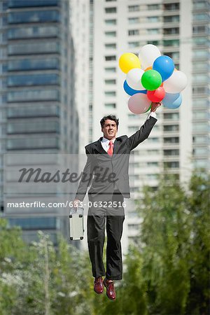 Homme d'affaires emportée par bouquet de ballons