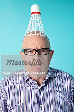 Porträt der böse Mann mit Federball auf Kopf über farbigen Hintergrund Porträt der böse Mann mit Federball auf Kopf über farbigen Hintergrund