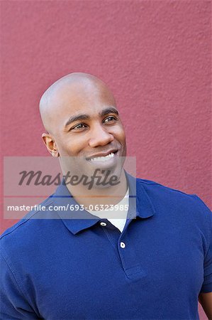 Happy bald African American man looking away over colored background