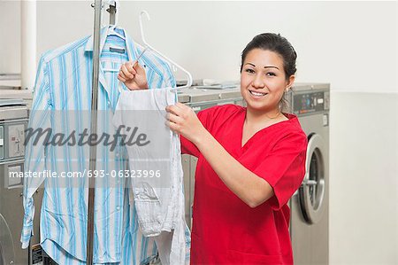 Portrait d'une jeune femme heureuse avec chemise suspendue dans la laverie