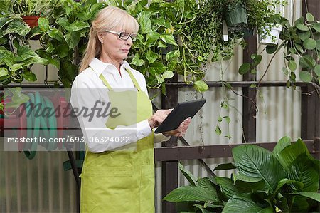 Senior gardener using digital tablet in garden center