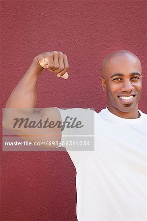 Portrait of an African American male flexing muscles over colored background