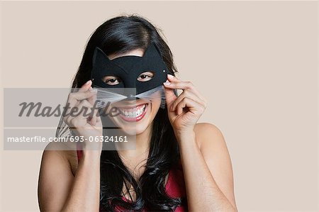 Portrait of a cheerful young woman wearing eye mask over colored background