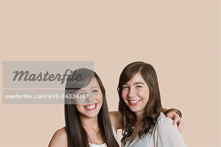 Portrait of young female friends over colored background