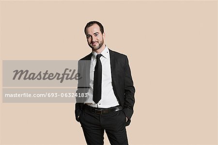 Portrait of a young businessman with hands in pockets over colored background
