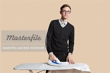 Portrait of a mid adult man looking away while ironing over colored background